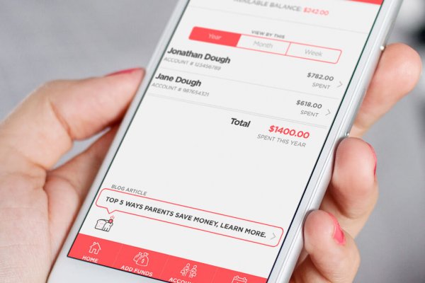 woman holding iPhone with Lunch Money Buddy app showing both kids accounts of how much they have spent and helpful blog article on ways to save money on lunches at the bottom